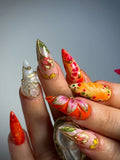 Handmade press-on nails with bold red, orange, and gold 3D floral butterfly designs