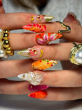 Handmade press-on nails with bold red, orange, and gold 3D floral and butterfly designs.