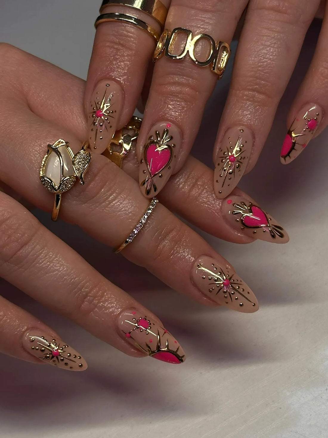Handmade press-on nails with pink hearts, gold chrome accents, and rhinestone starburst design.