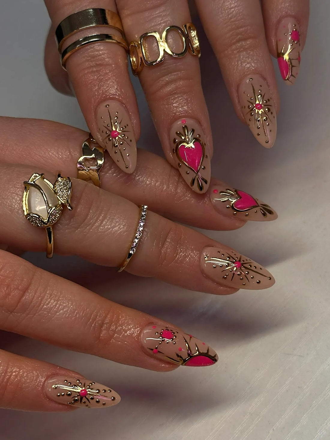 Handmade press-on nails with pink hearts, gold chrome accents, and rhinestone starburst design.