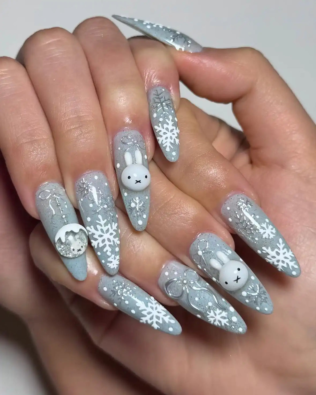 Handmade press-on nails with bunny, snowflake, and glitter winter Christmas designs.