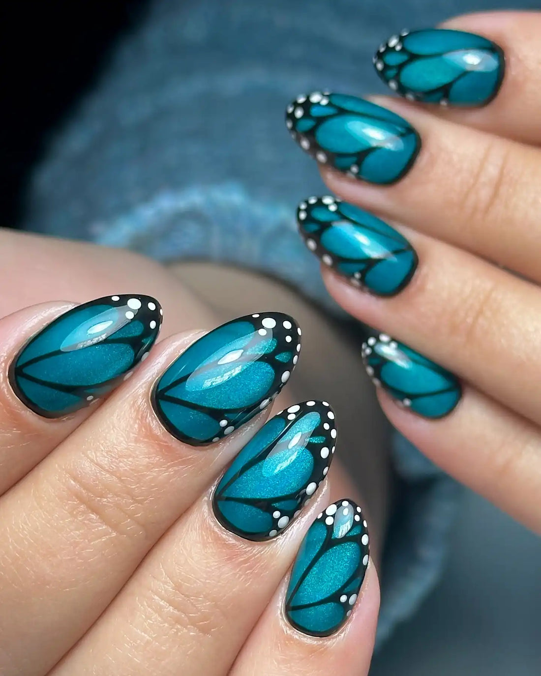 Handmade press-on nails with teal butterfly wing design and white dot accents