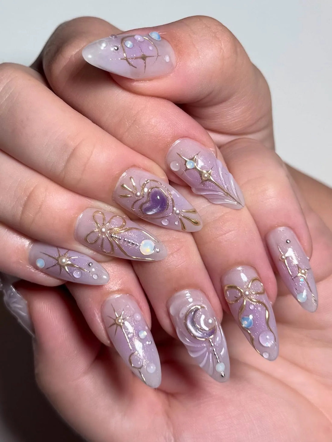 Handmade purple stiletto press-on nails with celestial gold accents and heart designs