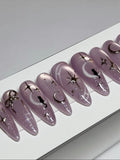 Handmade purple stiletto press-on nails with moon, star, and cat celestial designs