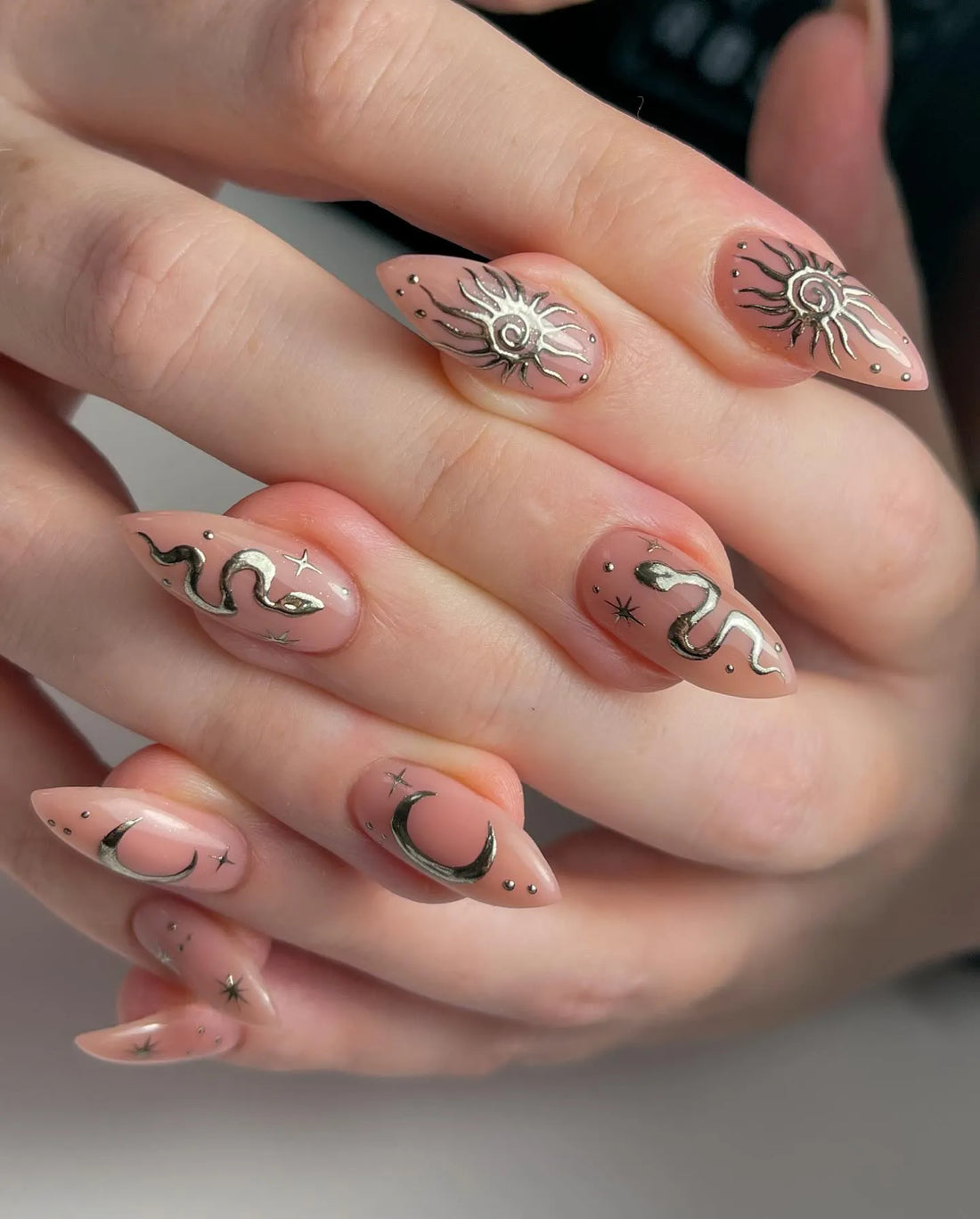 Handmade nude press-on nails with gold chrome sun, moon, snake, and star celestial art.