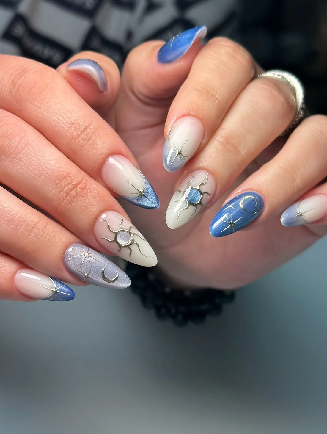 Handmade celestial press-on nails with sun, moon, and star designs in blue and nude shades