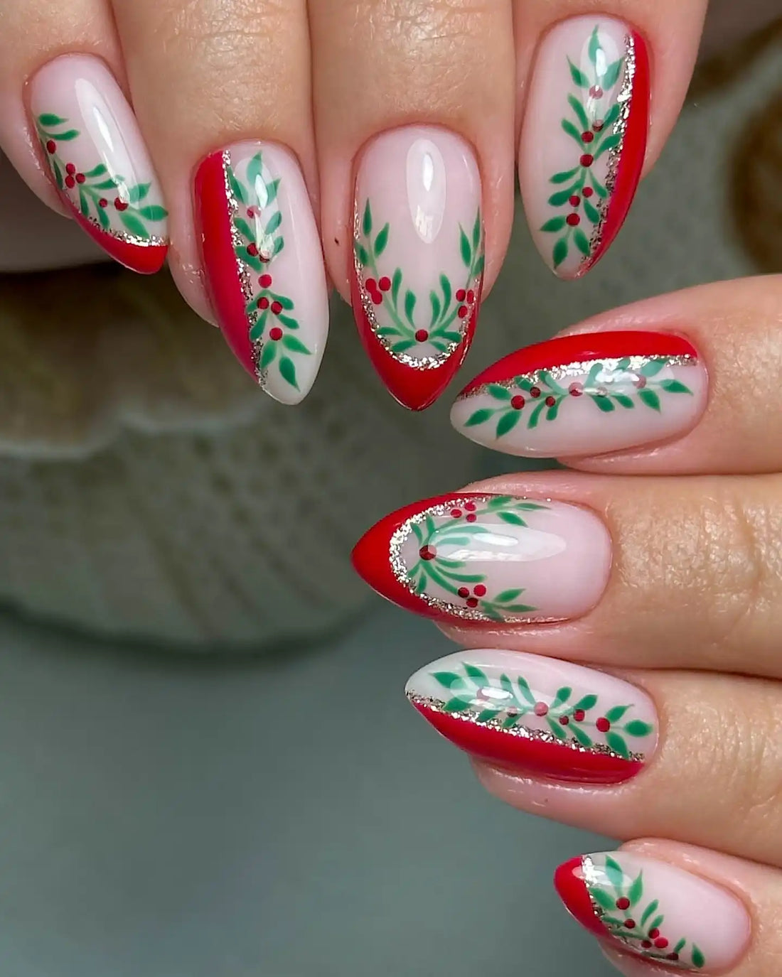 Handmade Christmas press-on nails with red tips, green holly leaves, and red berry designs.