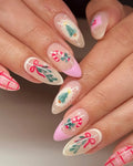 Handmade Christmas press-on nails with pink plaid, candy cane, wreath, and tree designs.