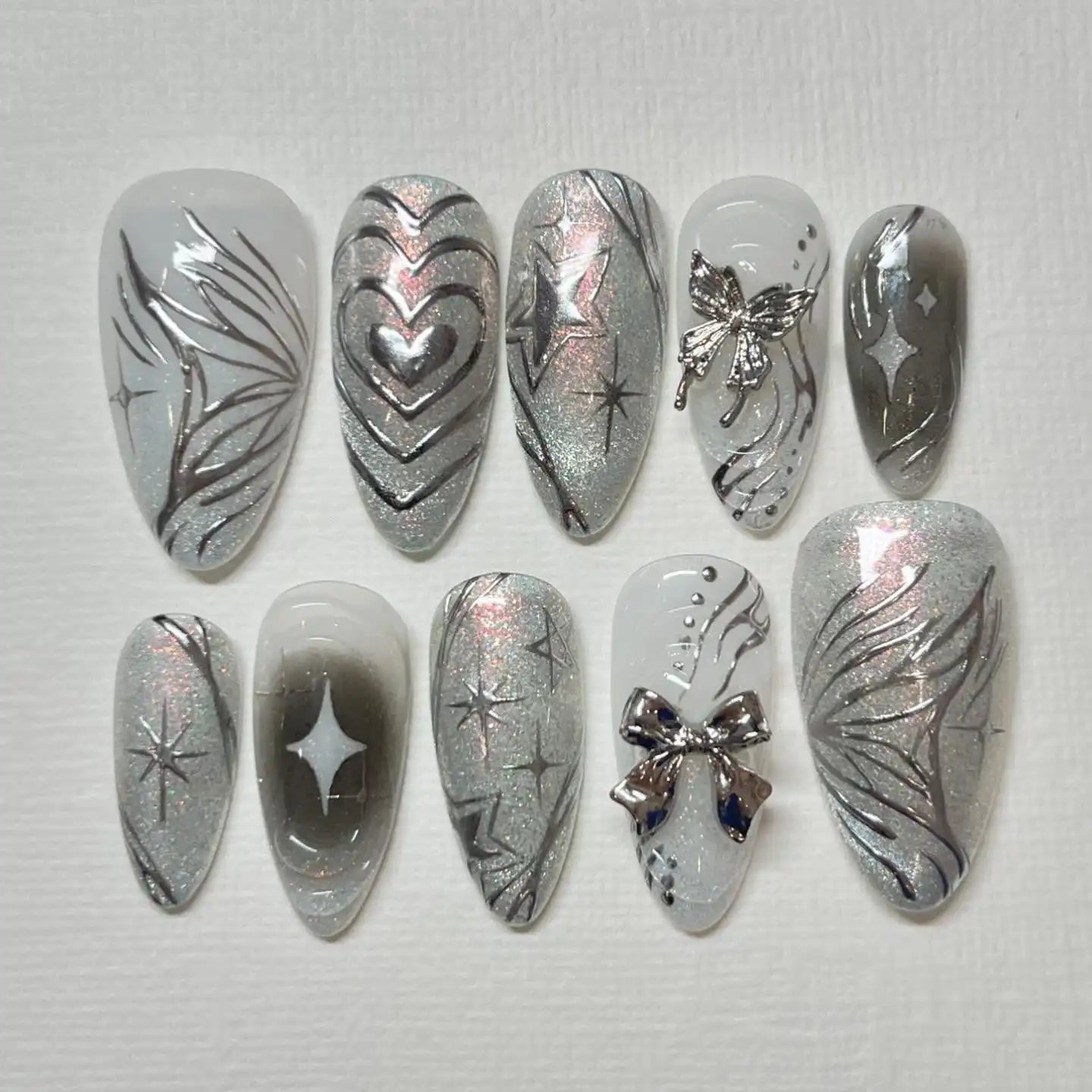 Handmade silver press-on nails with butterfly, heart, star, and abstract designs