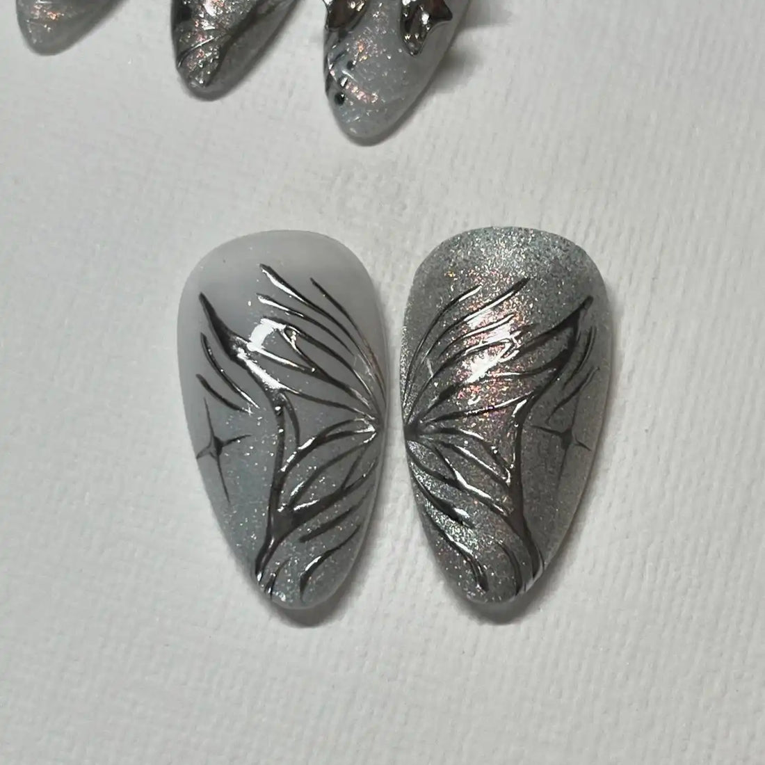 Handmade silver press-on nails with butterfly, heart, star, and abstract designs