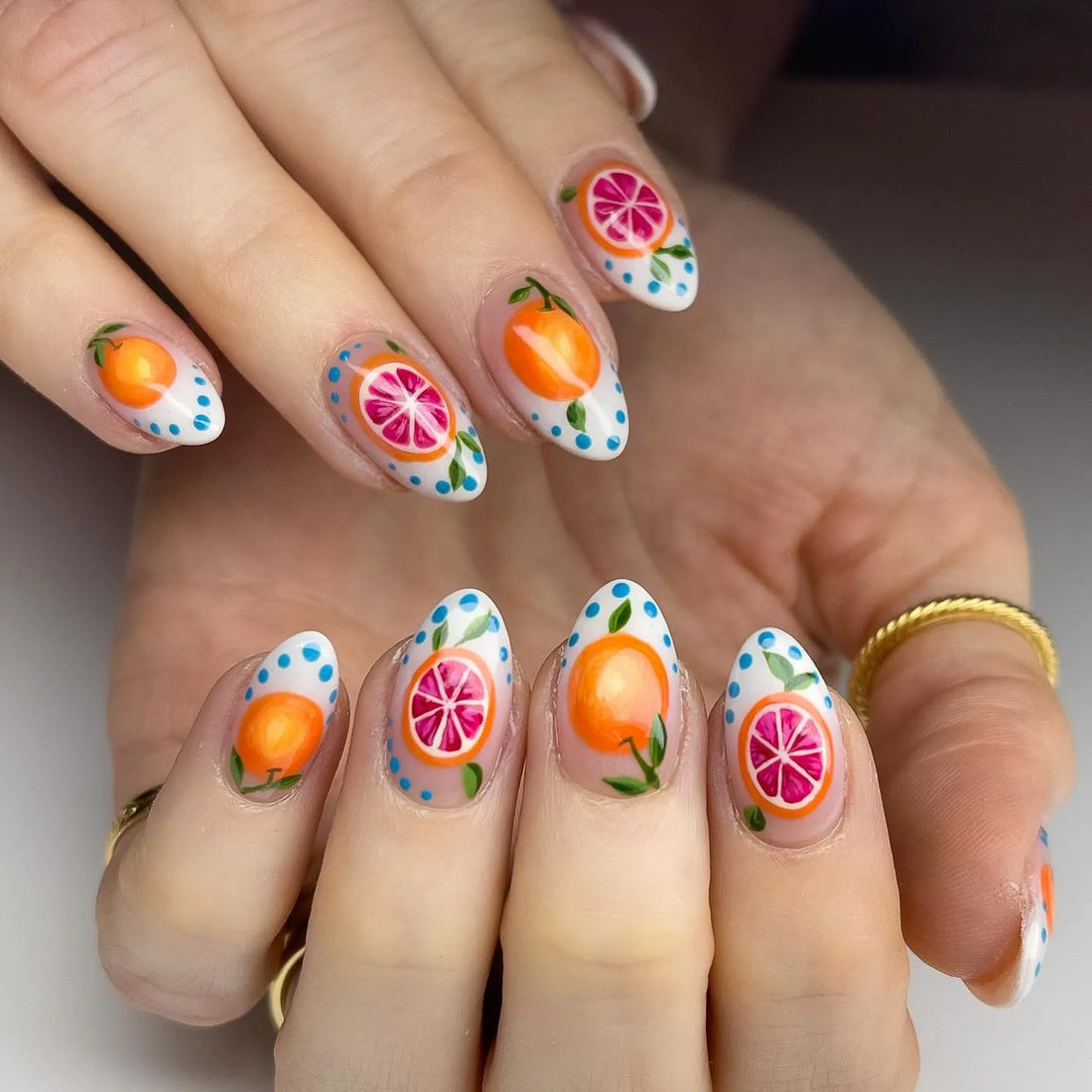 Handmade press-on nails with orange and grapefruit fruit art, summer-themed nail design.