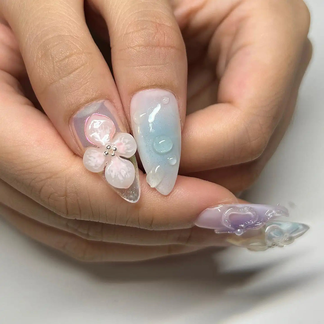 Handmade clear spring press-on nails with 3D blossom and butterfly designs, pastel accents