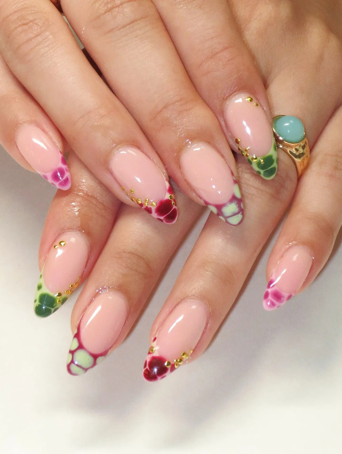 Handmade press-on nails with colorful reptile print French tips and gold accents.