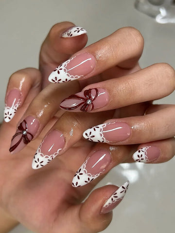 Handmade French tip press-on nails with white lace, floral patterns and 3D red bow accents.