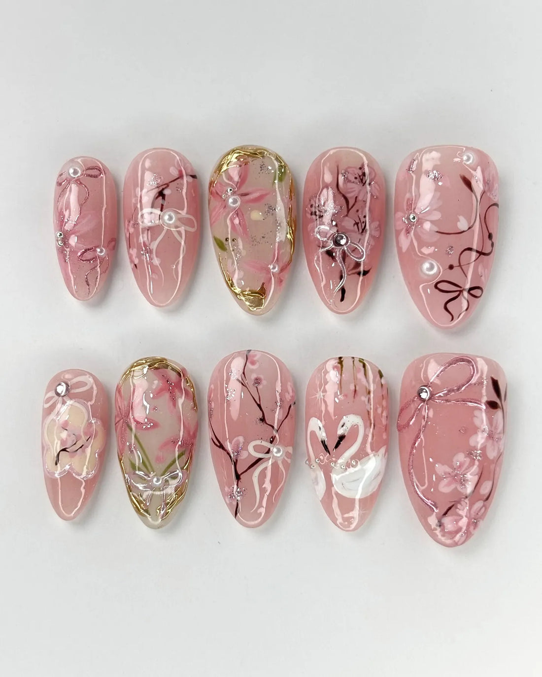 Handmade pink press-on nails with cherry blossom, ribbon, swan, and pearl accents.