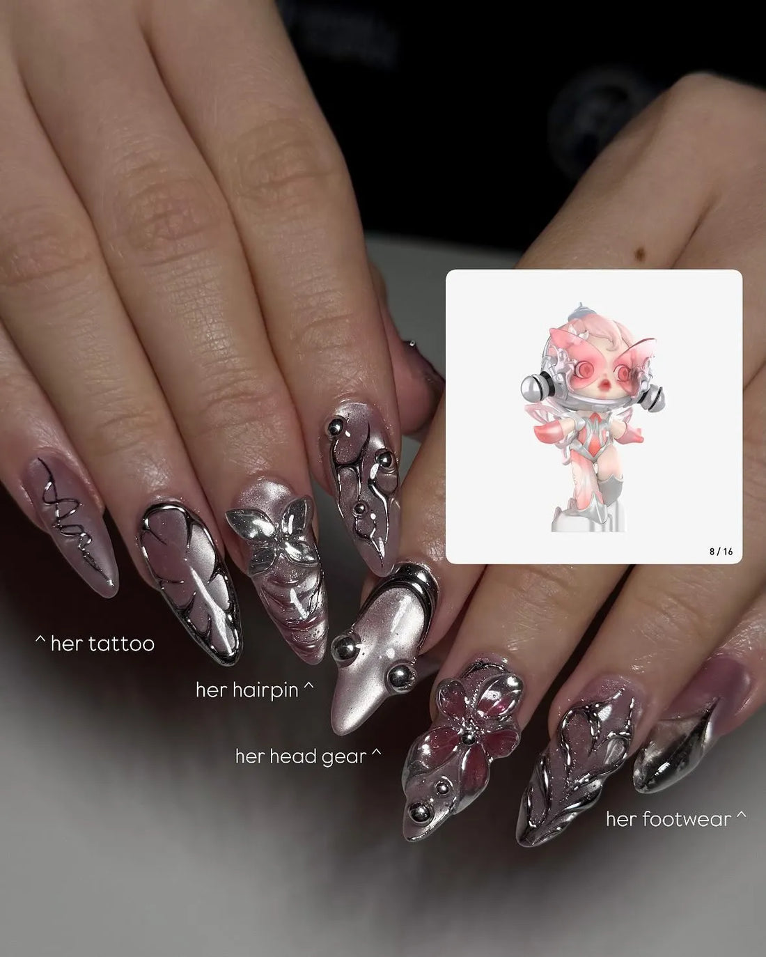 Hand with long stiletto press-on nails featuring chrome pink metallic 3D floral designs