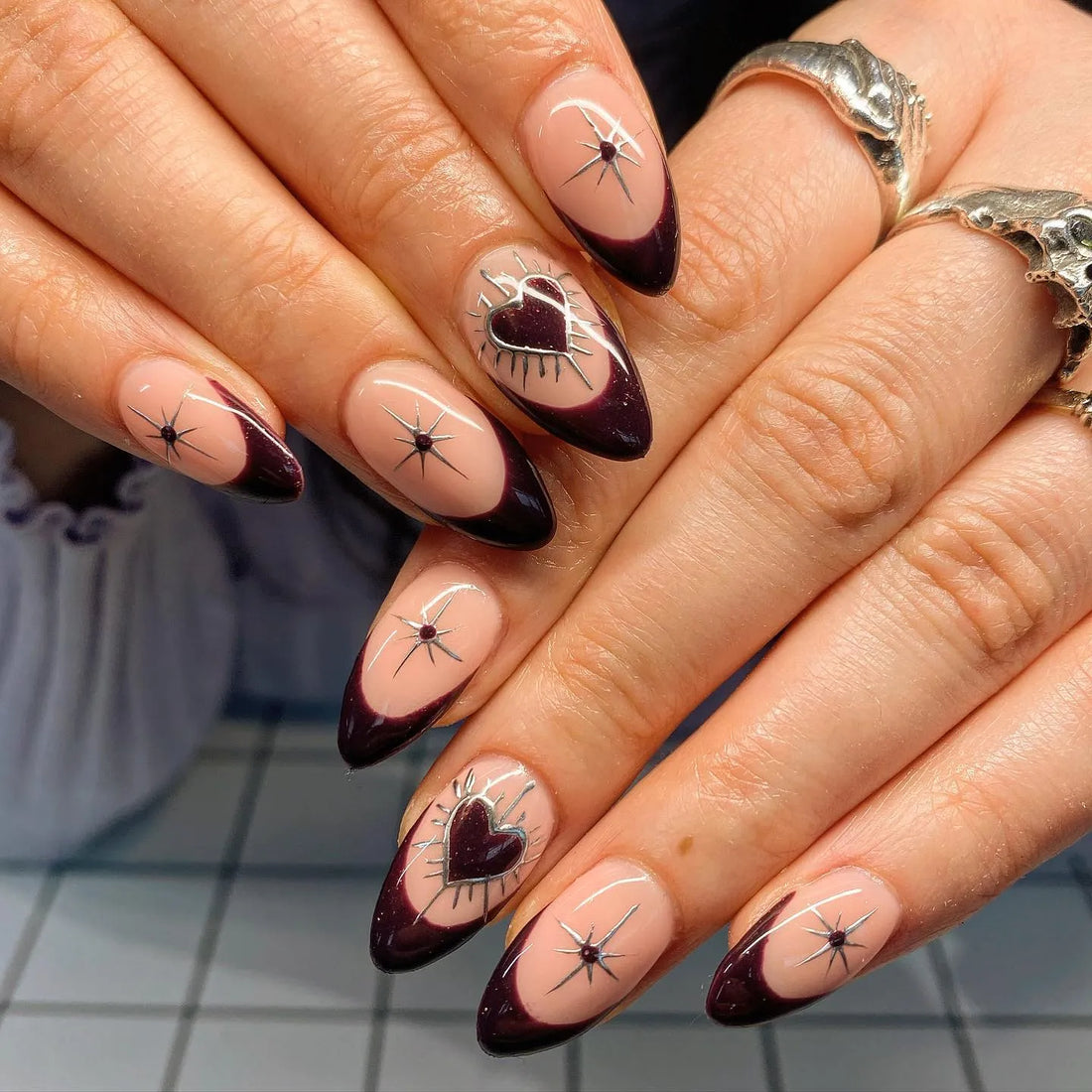 Handmade almond press-on nails with dark burgundy French tips, silver hearts, and star accents