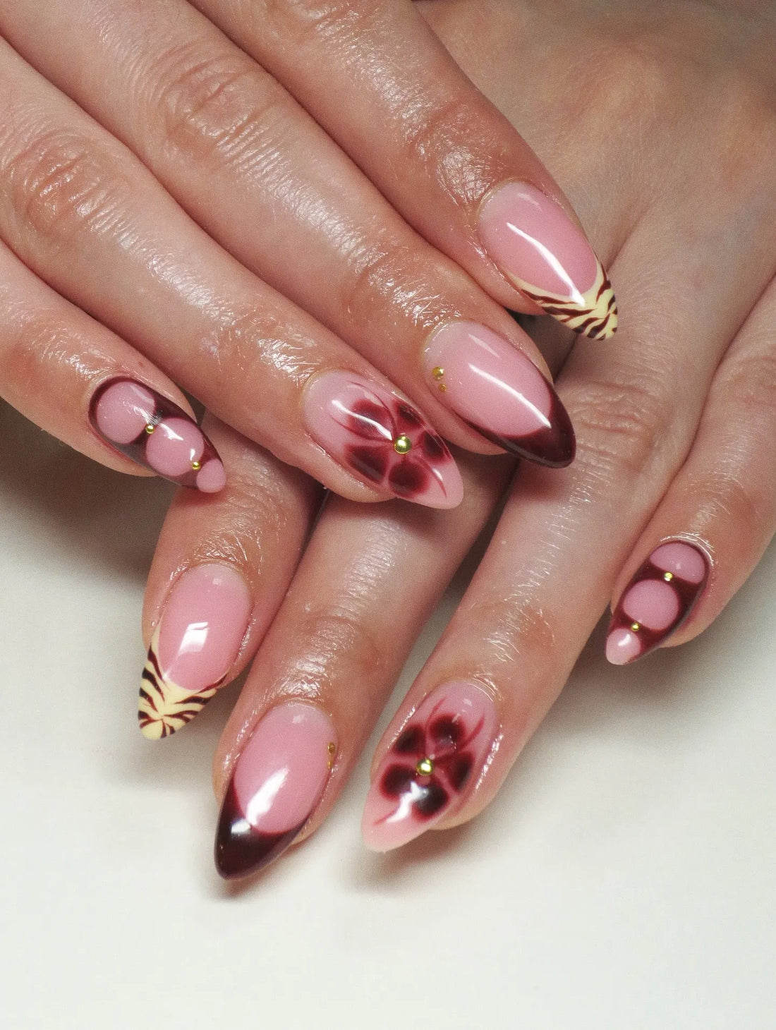 Handmade press-on nails with dark cherry French tips, floral and tiger print accents.