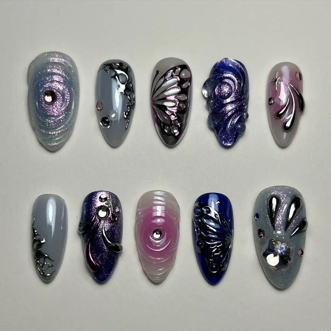 Handmade purple and silver press-on nails with chrome butterfly and rhinestone designs