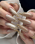 Handmade taupe press-on nails with gold chrome edges and rhinestone accents.