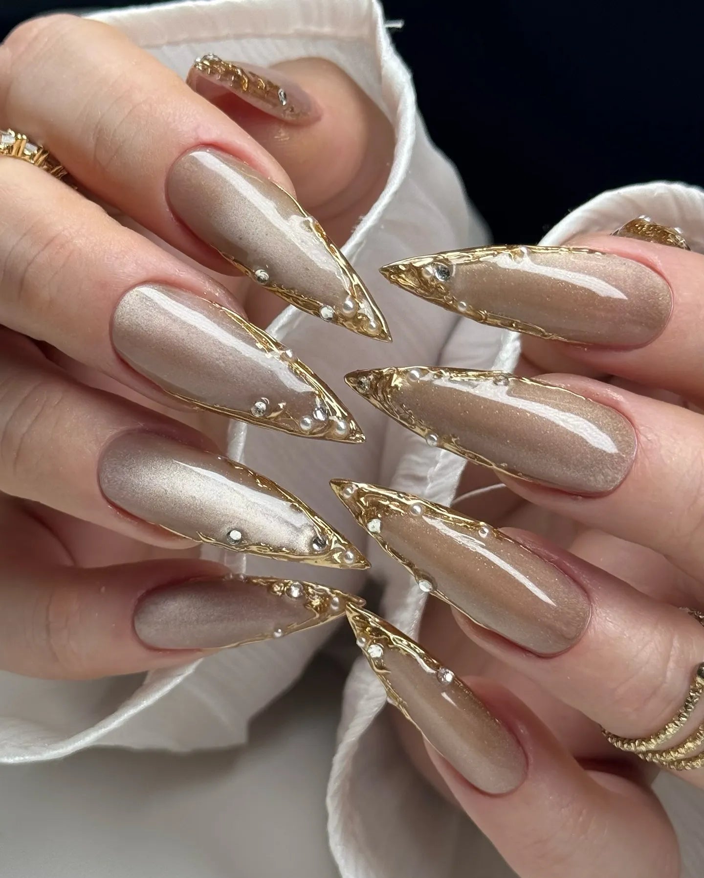 Handmade taupe press-on nails with gold chrome edges and rhinestone accents.