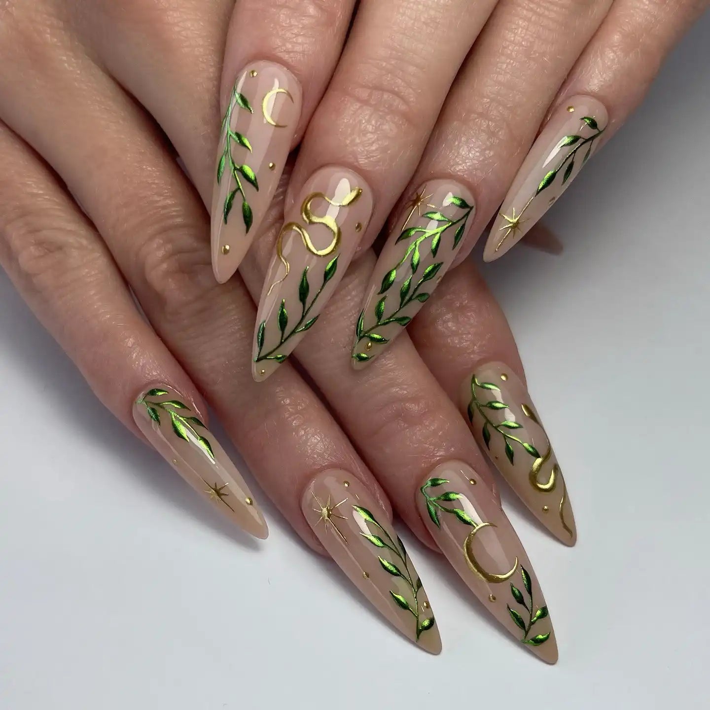 Handmade press-on nails with emerald green vines, gold moons, stars, and snake designs.