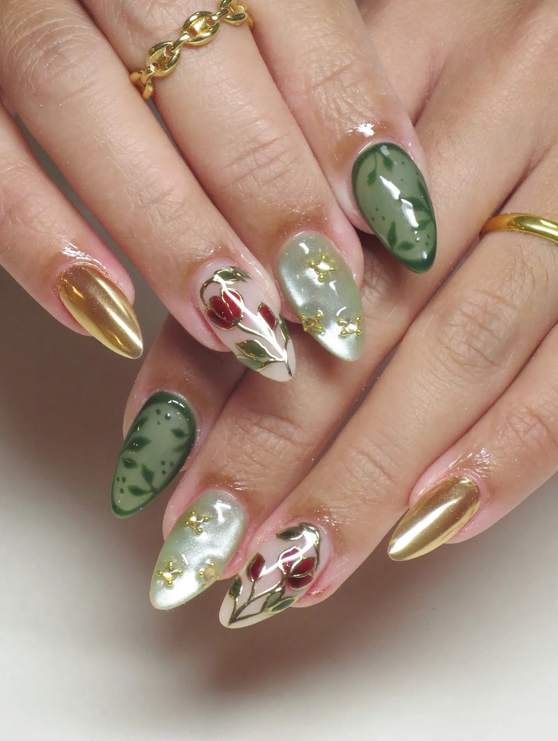 Handmade green and gold press-on nails with rose and vine designs, cat eye shimmer finish