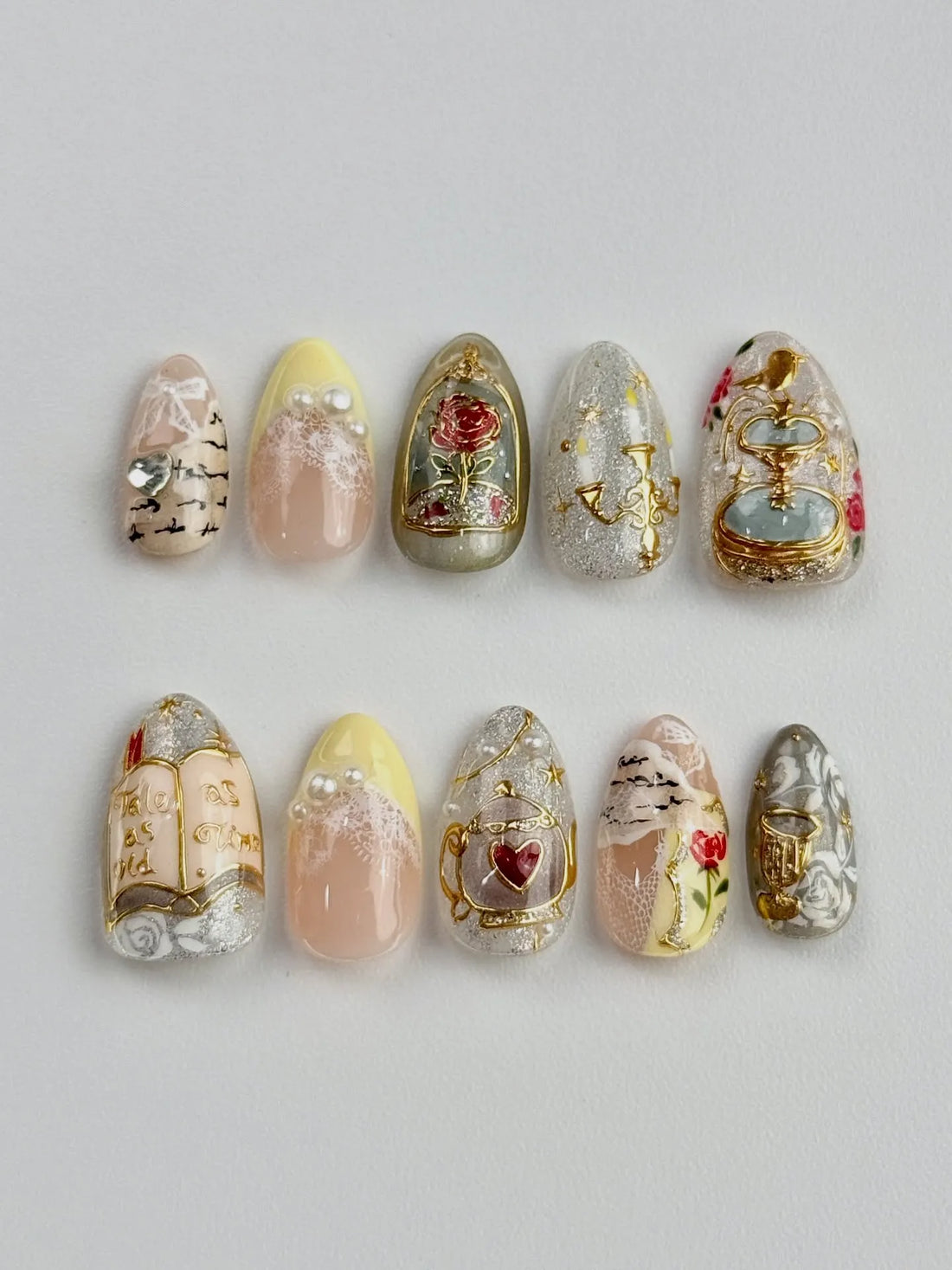 Handmade fairytale press-on nails with gold rose, book, chandelier, pearl, and floral accents.