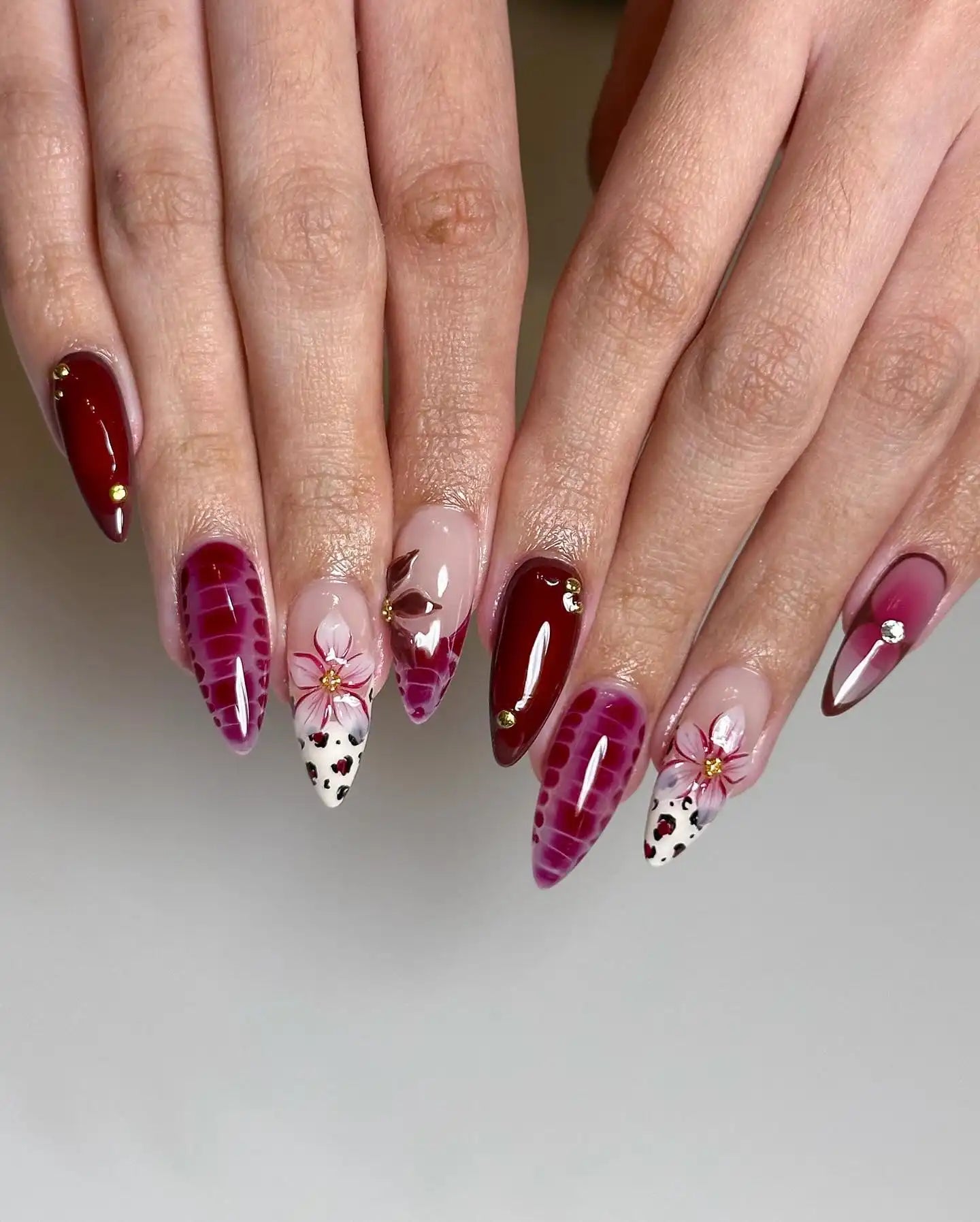 Handmade red and purple press-on nails with floral and heart designs, spring nail art