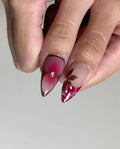 Hand with handmade red floral spring press-on nails featuring rhinestone accents.