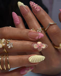Hand with pink and yellow 3D flower sculpted press-on nails, spring floral nail art
