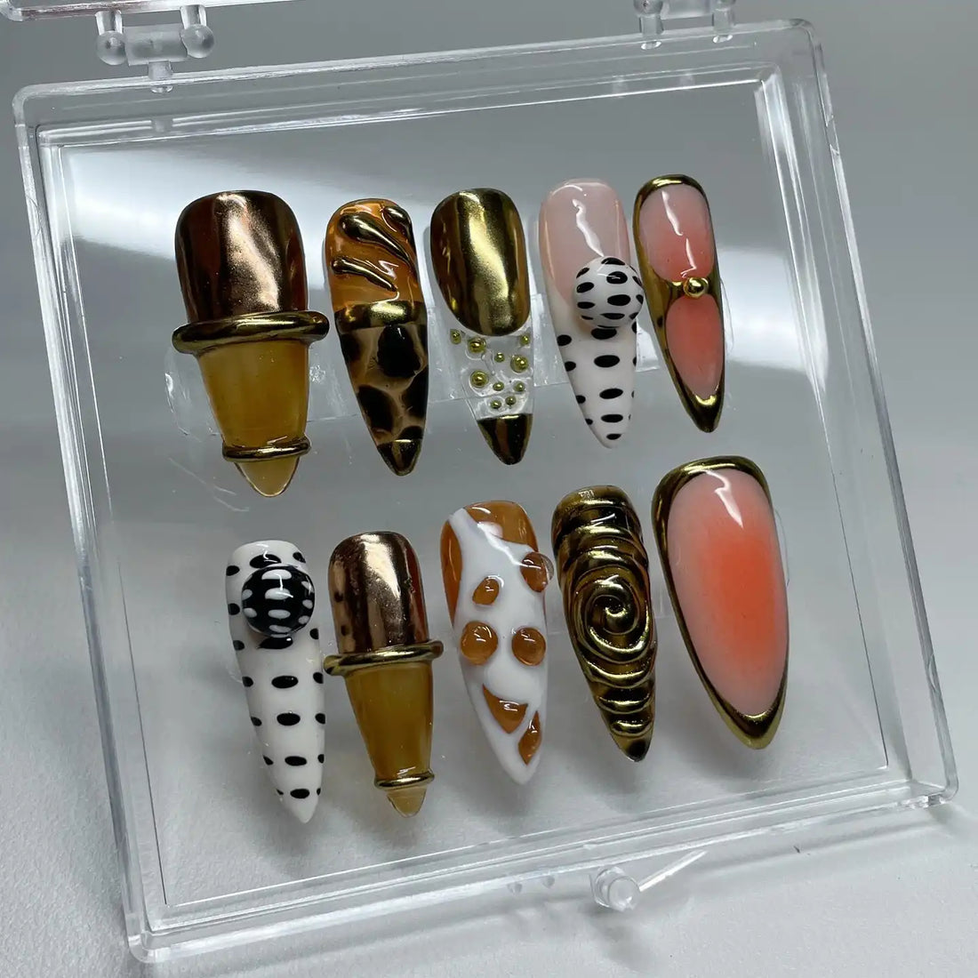Handmade press-on nails with gold chrome, polka dots, giraffe pattern, and swirl accents.