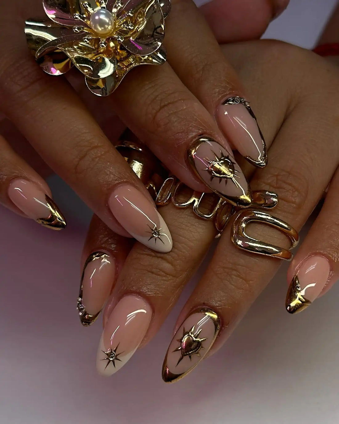 Handmade nude glossy press-on nails with gold chrome heart and celestial designs.