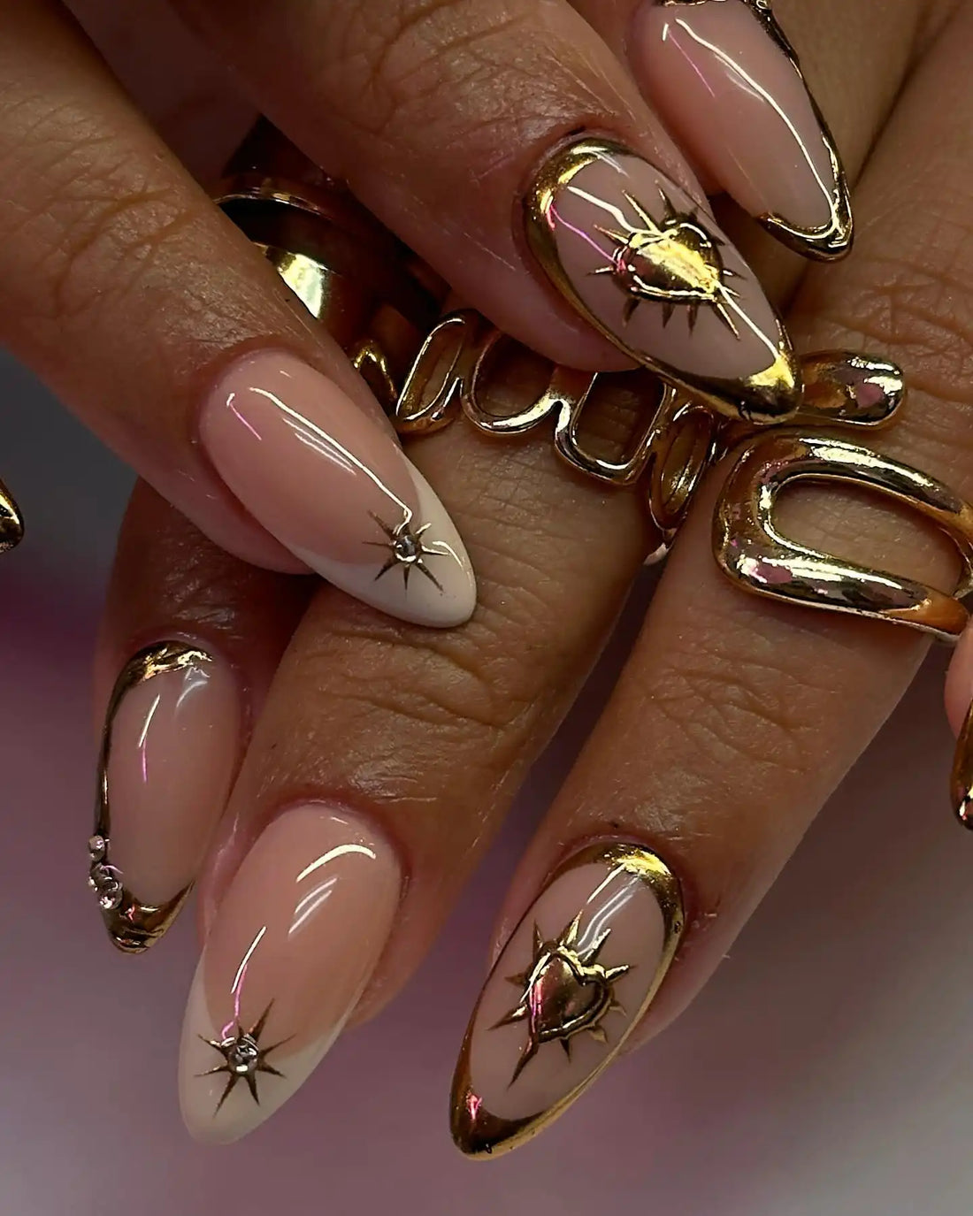Handmade nude glossy press-on nails with gold chrome heart and celestial designs.
