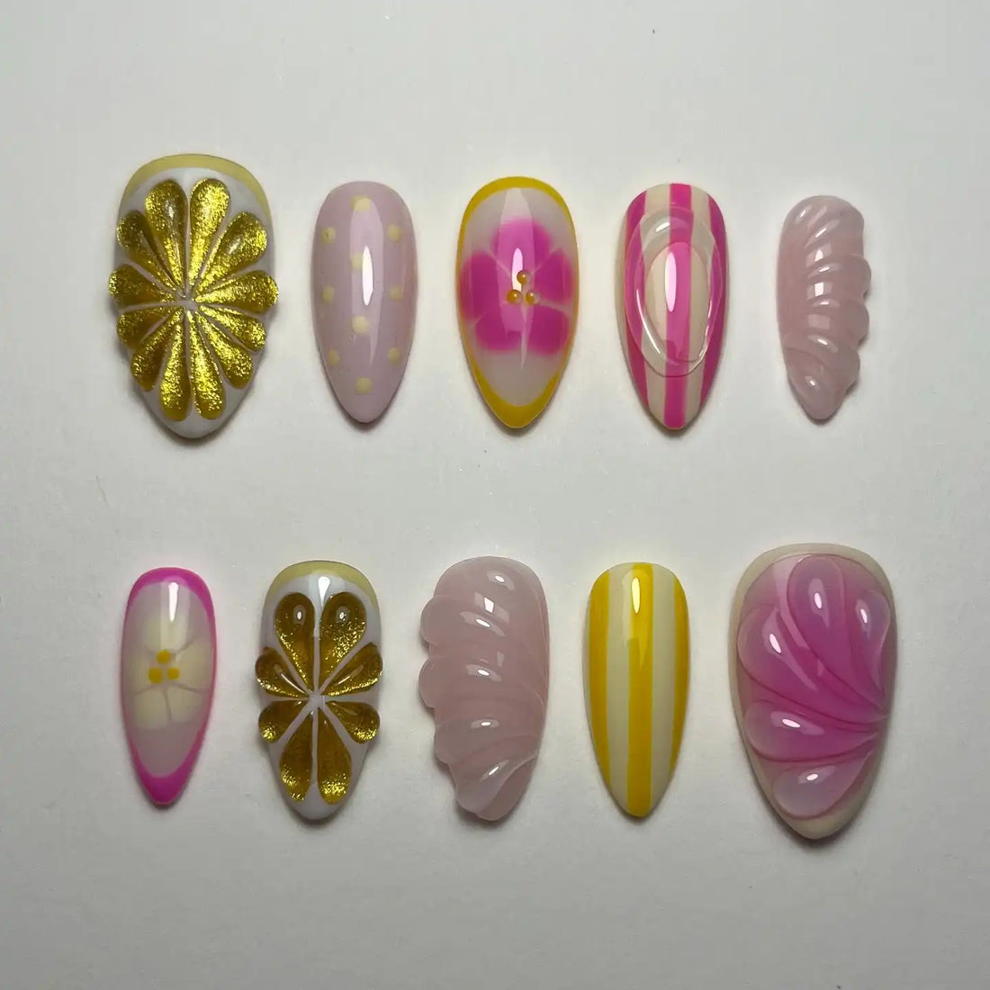 Handmade press-on nails with gold floral, pink stripe, and abstract summer designs.