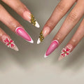 Hand with handmade pink and white French tip press-on nails, gold beads, and 3D floral art.