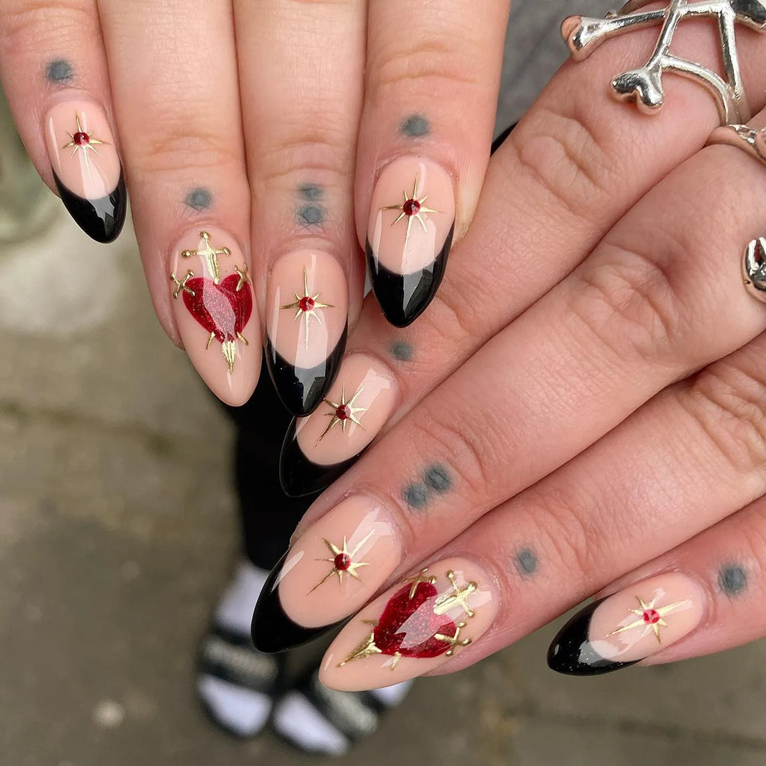 Handmade press-on nails with black French tips, gold stars, and red heart accents.