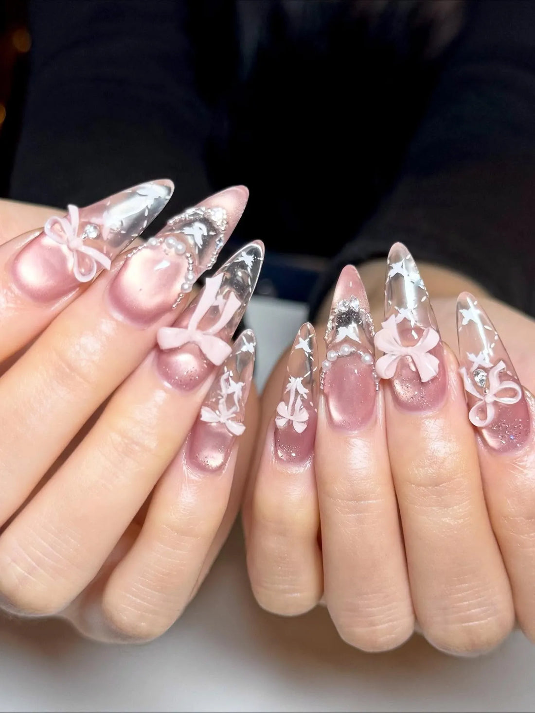 Handmade stiletto press-on nails with pink bows, pearls, stars, and celestial nail art.