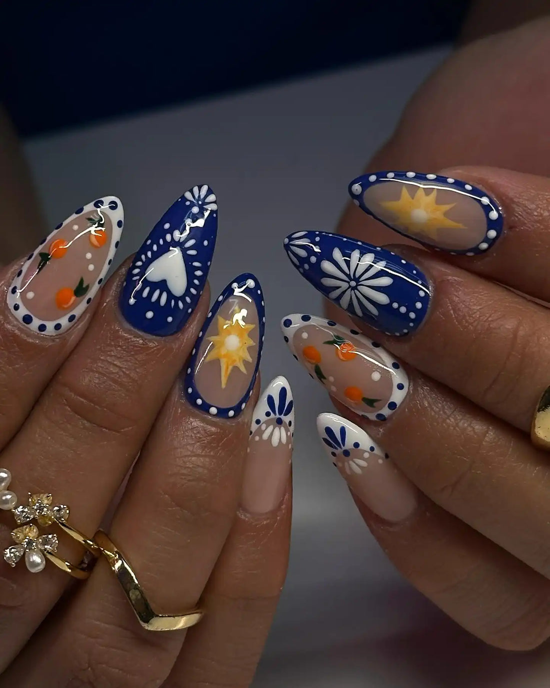 Handmade glossy press-on nails with blue, citrus, floral, heart, and sun designs.