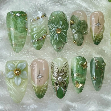 Handmade green floral press-on nails with pearl, butterfly, and gold garden accents.