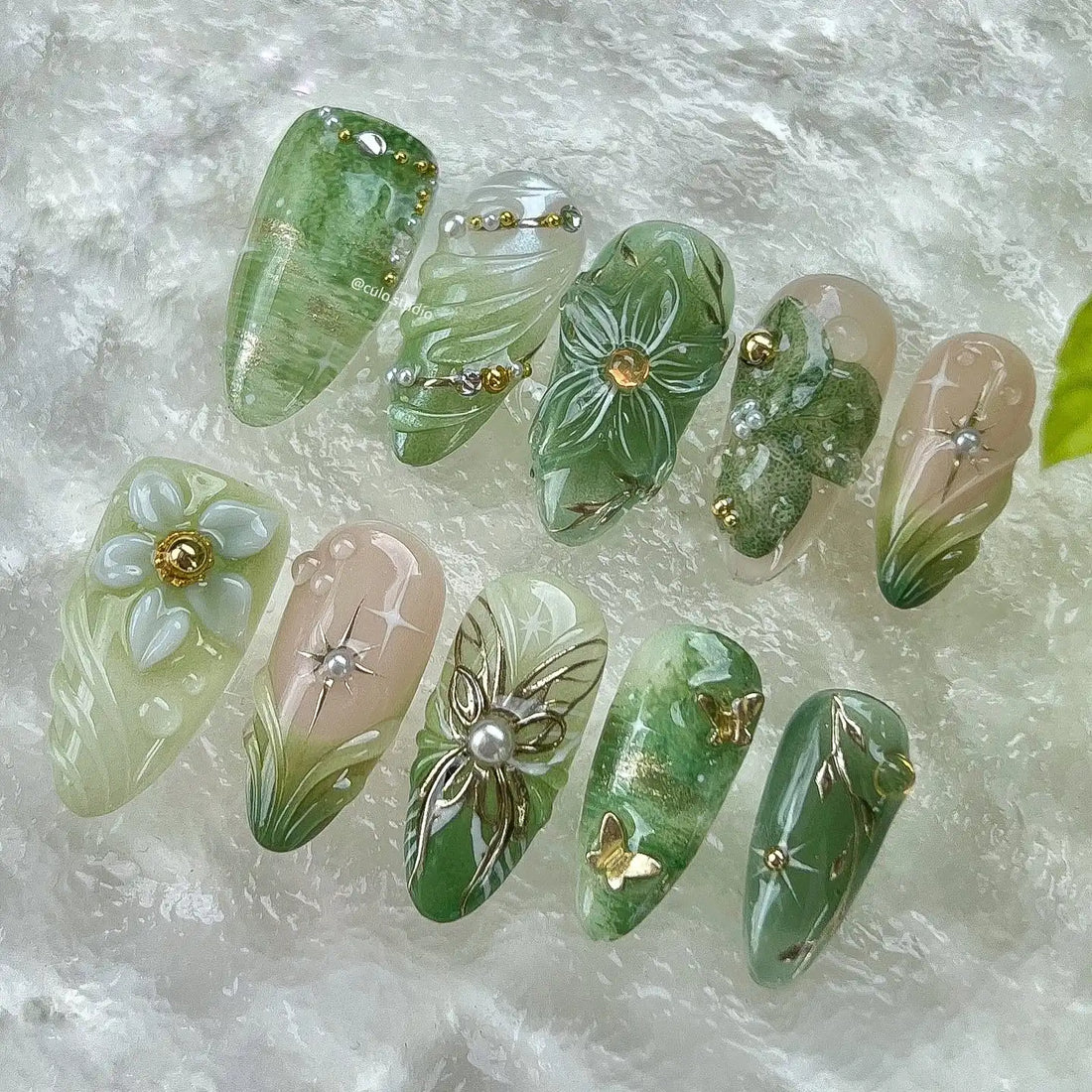 Handmade green floral press-on nails with pearl, butterfly, and gold garden accents.