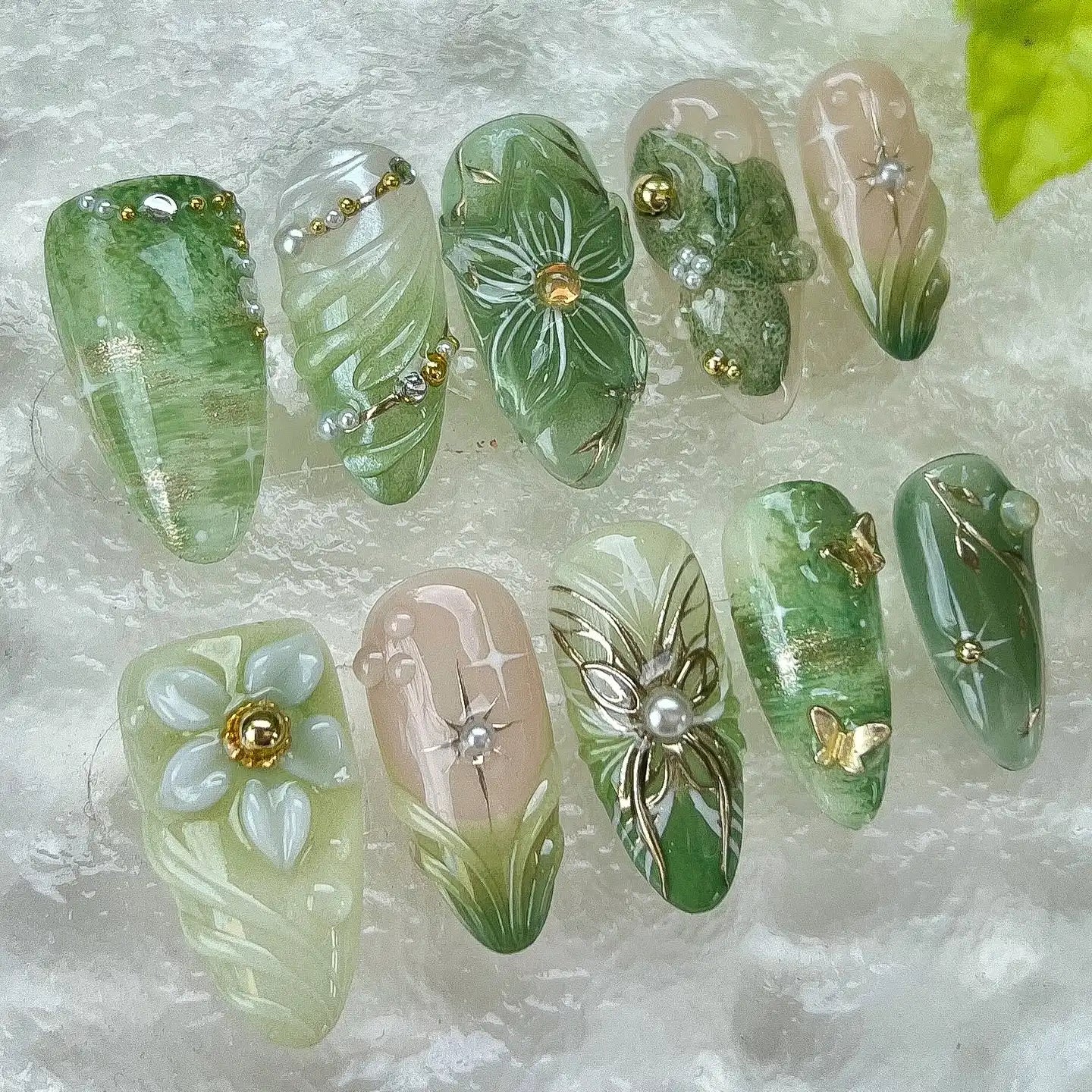 Handmade green floral press-on nails with pearl and butterfly garden fantasy designs.