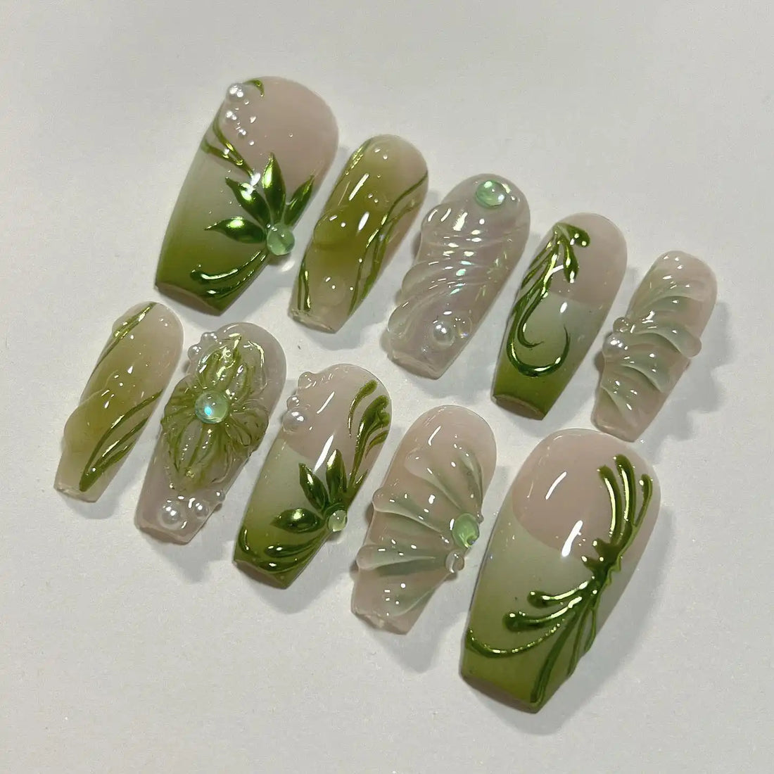Handmade green leaf and floral press-on nails with 3D details on a neutral background