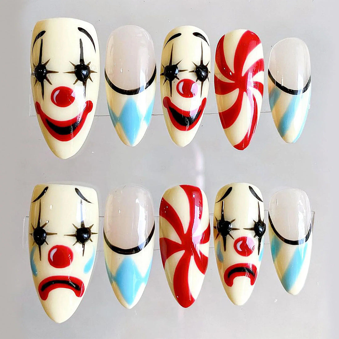 Handmade press-on nails with Halloween moody clown faces and carnival swirl designs.