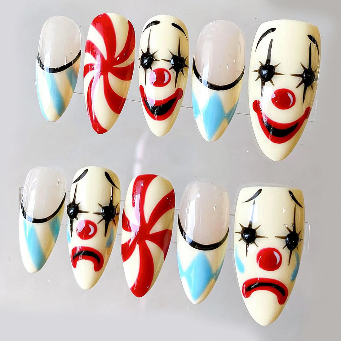 Handmade press-on nails with Halloween moody clown faces and carnival swirl designs.