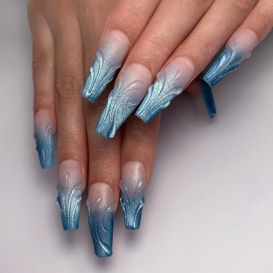 Hand with long icy blue shimmer 3D scalloped ombre French press-on nails