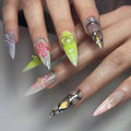 Hand with long handmade press-on nails featuring iridescent 3D floral and metallic designs
