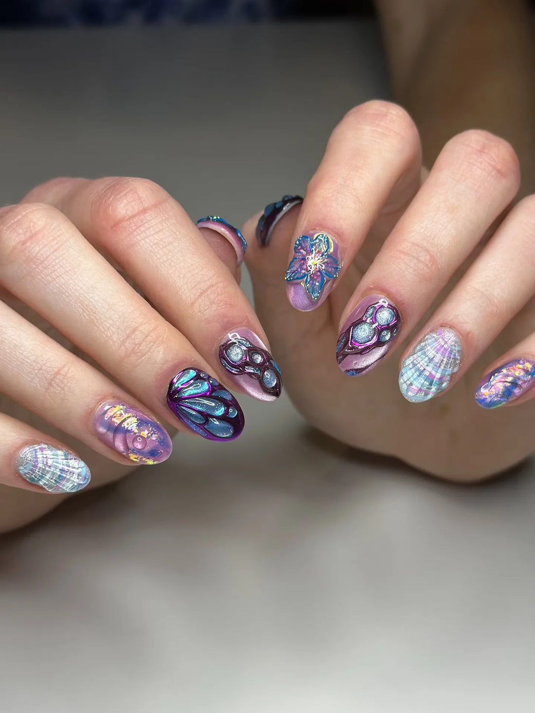 Handmade iridescent fantasy press-on nails with 3D butterfly, flower, and shell designs