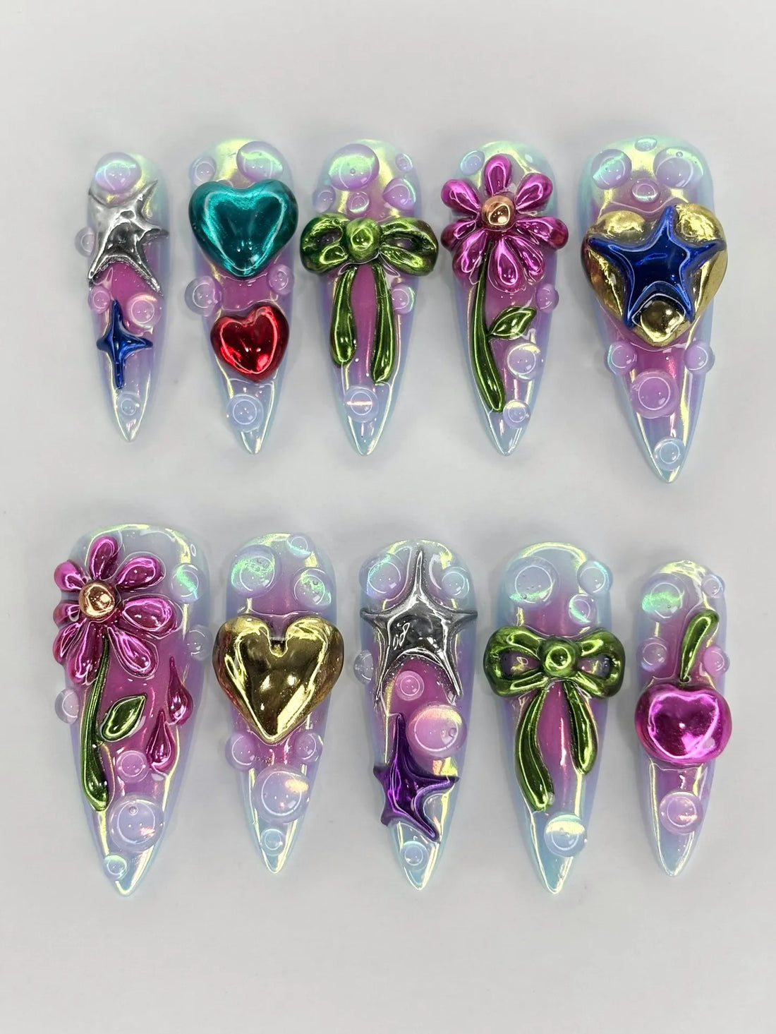 Handmade iridescent press-on nails with 3D metallic hearts, stars, bows, flowers, and cherries