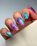 Hand with handmade iridescent neon plaid cat-eye shimmer press-on nails in blue and purple.